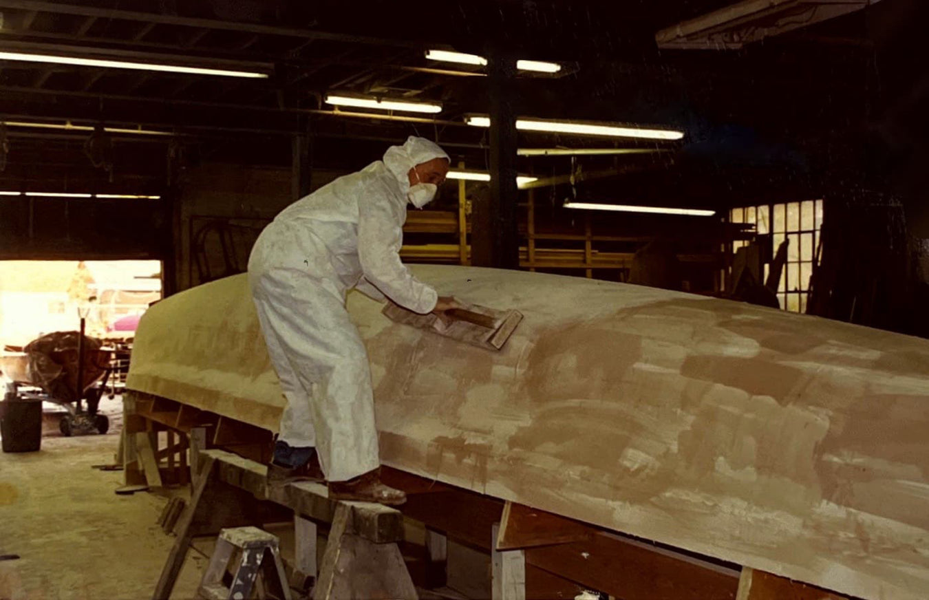 man sanding an unfinished boat